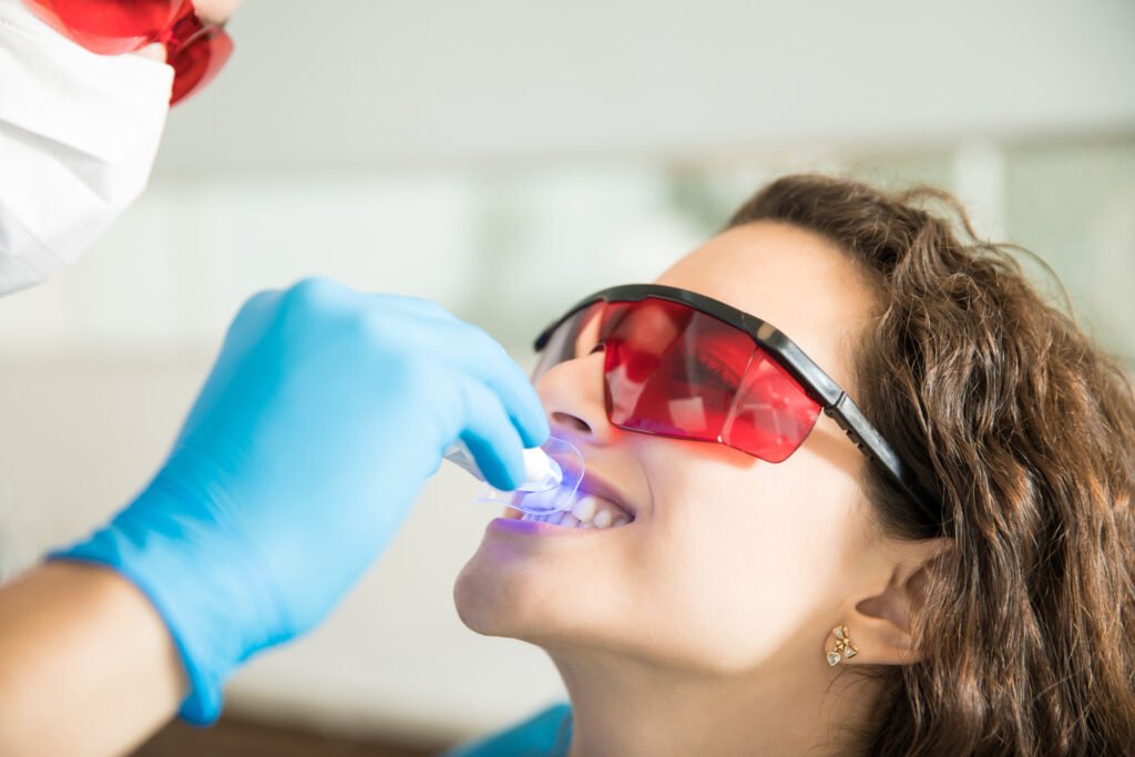 Klinikte UV ışıkla diş beyazlatma uygulaması yapılan kadın