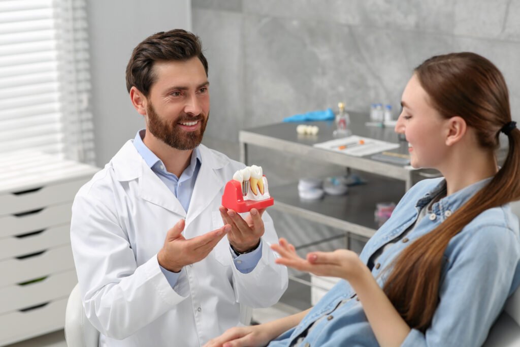 Diş hekimi implant modeliyle hastaya bilgi veriyor — implant fiyatları danışmanlığı